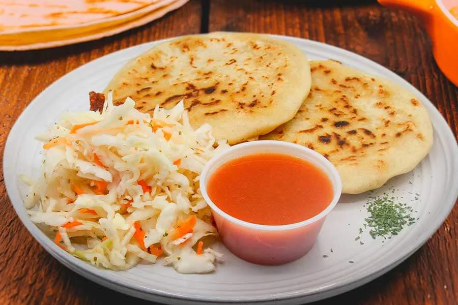 Plate with 2 arepas and salad with sauce on the side