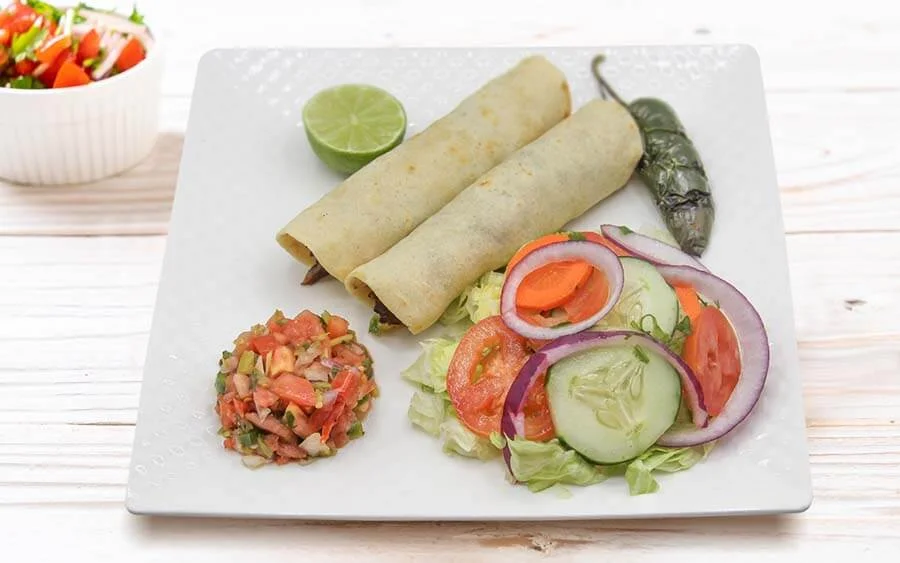  Square plate with two burritos, two salads and a lemon on the side