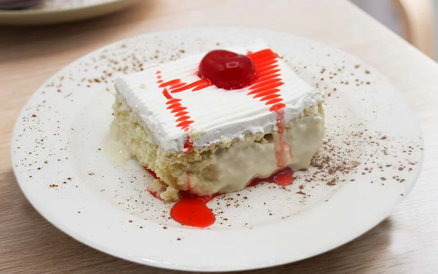 White dessert with white cream and red sauce with cherry 
