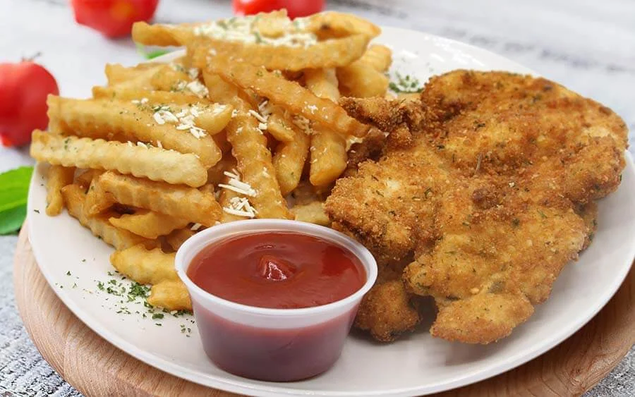 Chicken cutlet accompanied with French fries and tomato sauce 